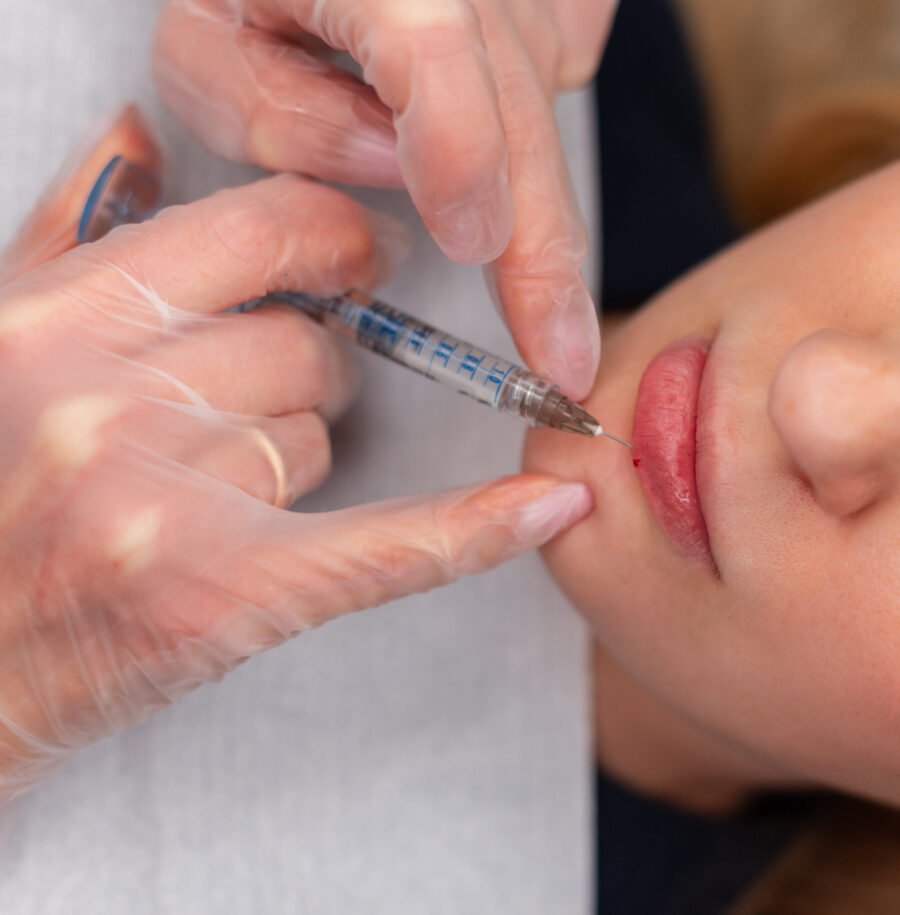 Professional woman cosmetologist makes correction and enlarges lips with filler injection in beauty clinic
